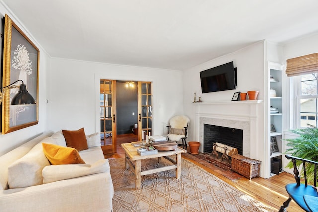 living room featuring wood-type flooring, crown molding, and a fireplace