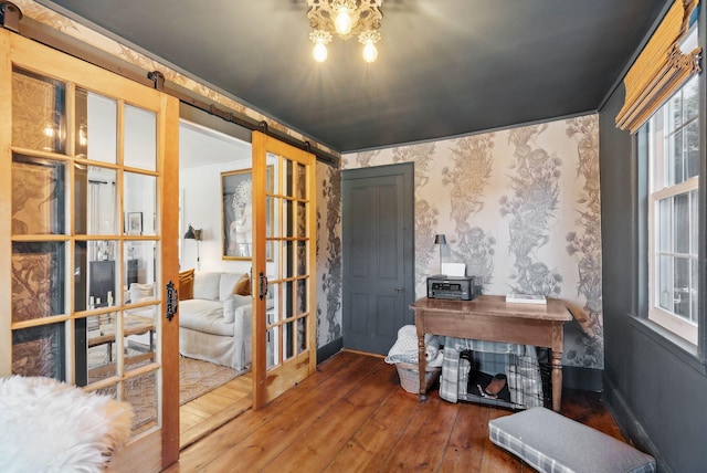 interior space with french doors, a barn door, ornamental molding, and hardwood / wood-style floors