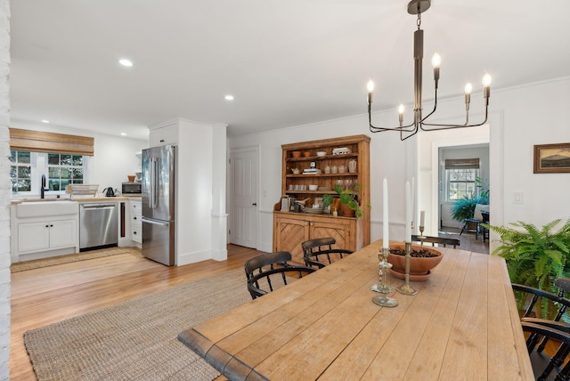 dining space featuring light wood-type flooring, a notable chandelier, and sink