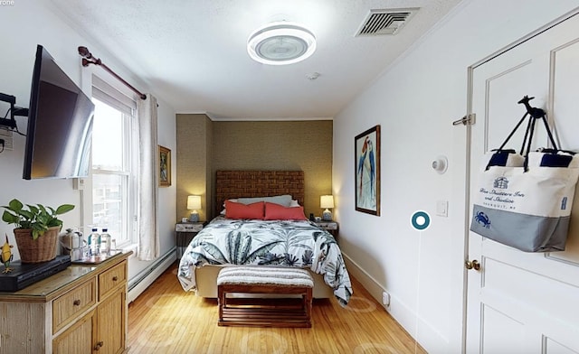 bedroom featuring a textured ceiling, light hardwood / wood-style flooring, and baseboard heating