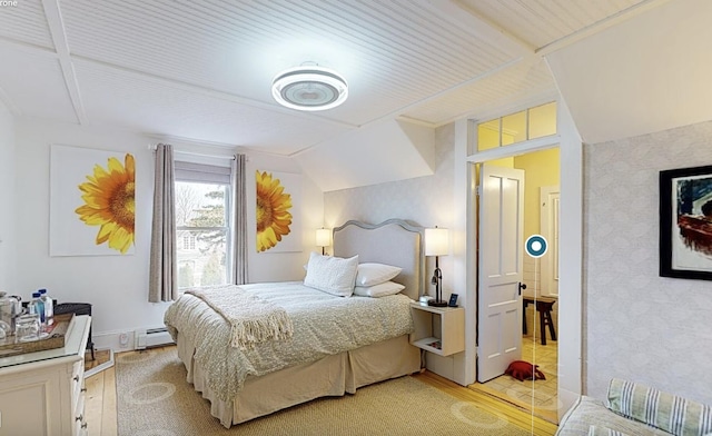 bedroom with lofted ceiling, light hardwood / wood-style floors, and a baseboard heating unit