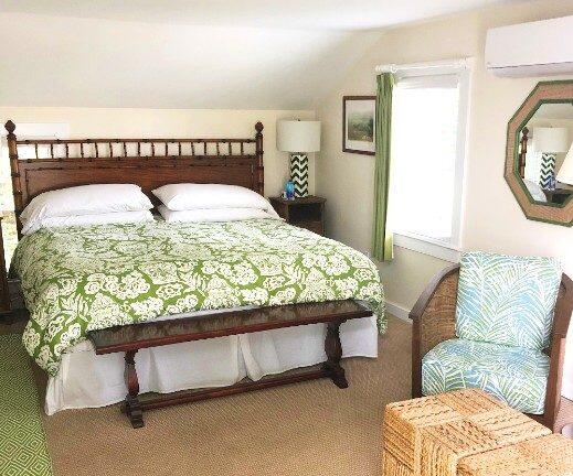 carpeted bedroom featuring an AC wall unit, multiple windows, and lofted ceiling