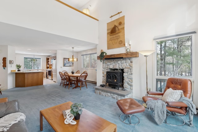 carpeted living room featuring a chandelier, a high ceiling, and a wood stove