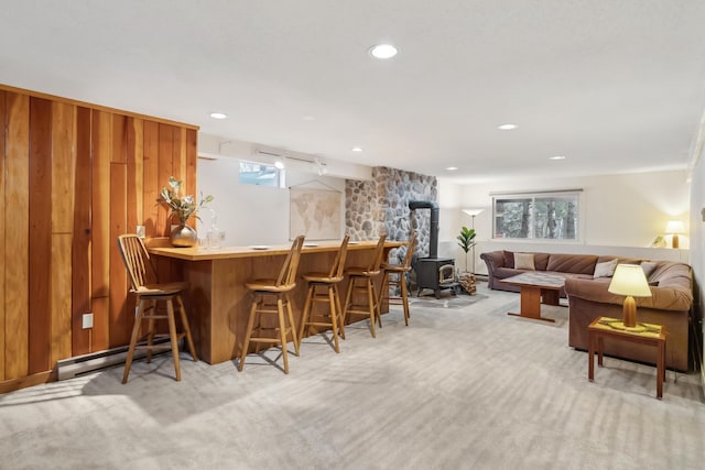 bar with a healthy amount of sunlight, light colored carpet, and a wood stove