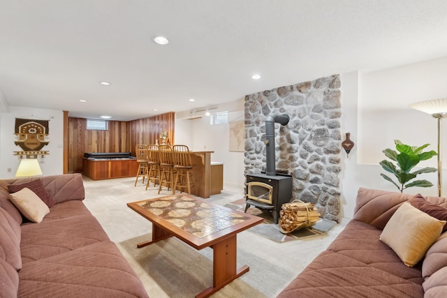 carpeted living room with indoor bar, a wood stove, and wooden walls