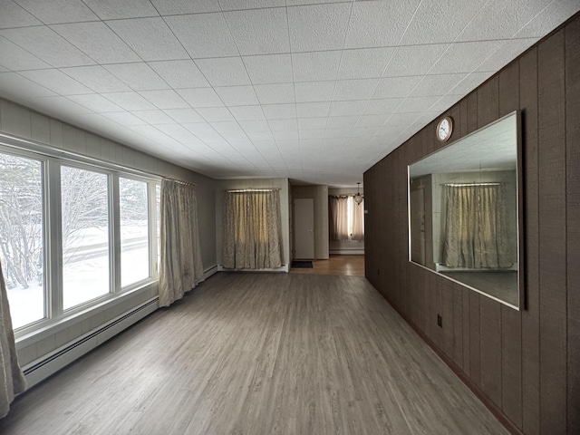 spare room featuring wood walls, hardwood / wood-style flooring, and a baseboard heating unit