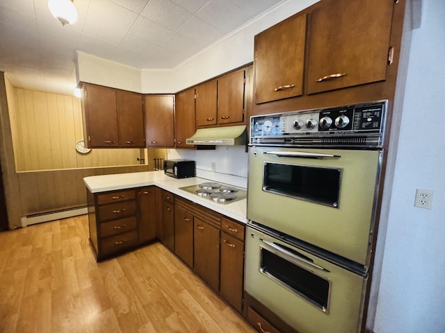 kitchen featuring wooden walls, stainless steel gas cooktop, double wall oven, light hardwood / wood-style flooring, and a baseboard radiator