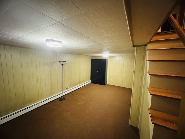 basement featuring a baseboard radiator and wood walls