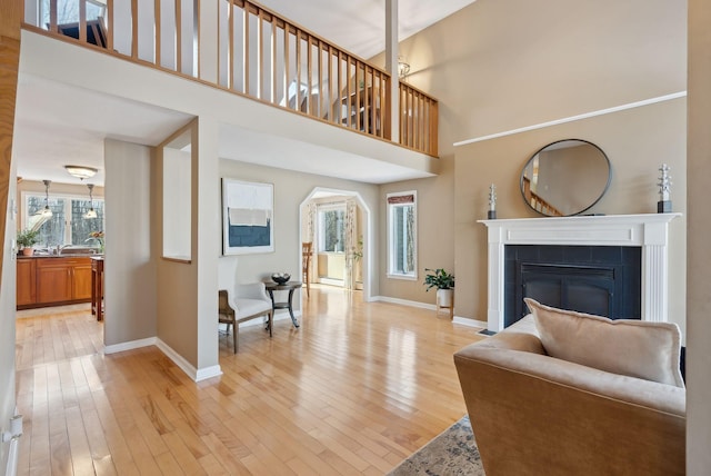 living room featuring a high ceiling, a tile fireplace, and light wood-type flooring