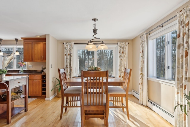 dining room with light hardwood / wood-style floors, baseboard heating, and an inviting chandelier