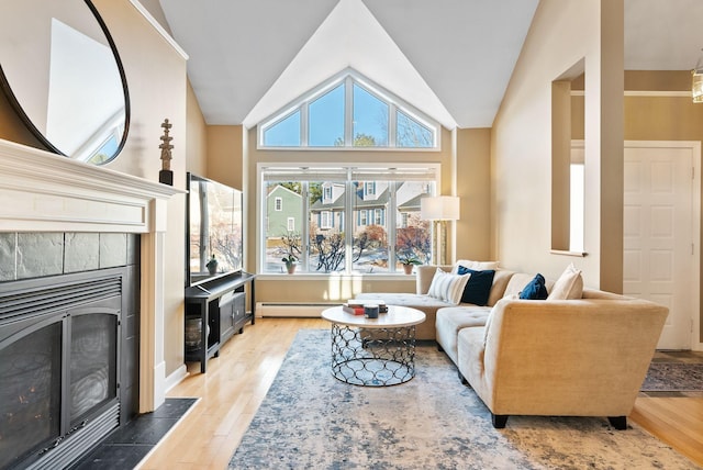 living room featuring baseboard heating, a tile fireplace, vaulted ceiling, and wood-type flooring