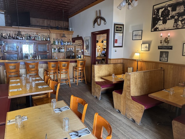 63 Main St, Bucksport, ME 04416 - dining room featuring a wainscoted wall, wood finished floors, wood walls, and a community bar