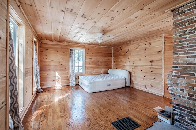 unfurnished bedroom featuring hardwood / wood-style floors, wooden walls, and wooden ceiling