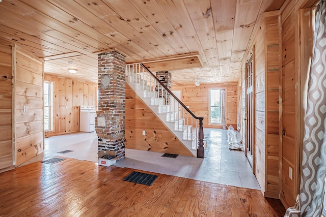 hall with wooden ceiling, wooden walls, light wood-type flooring, ornate columns, and washer / clothes dryer