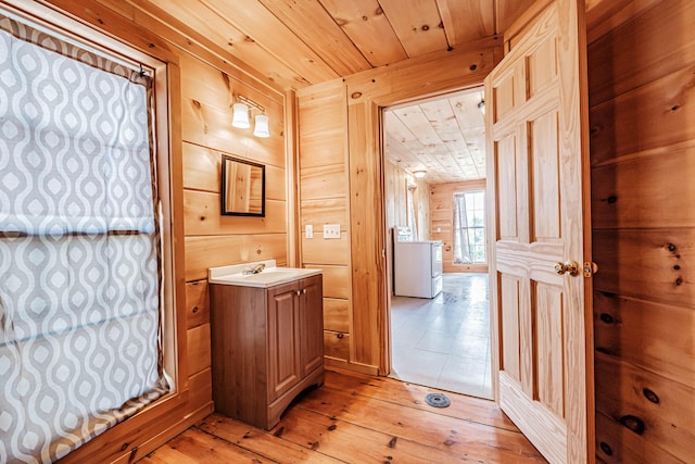 bathroom with wood ceiling, vanity, hardwood / wood-style floors, washer / clothes dryer, and wood walls