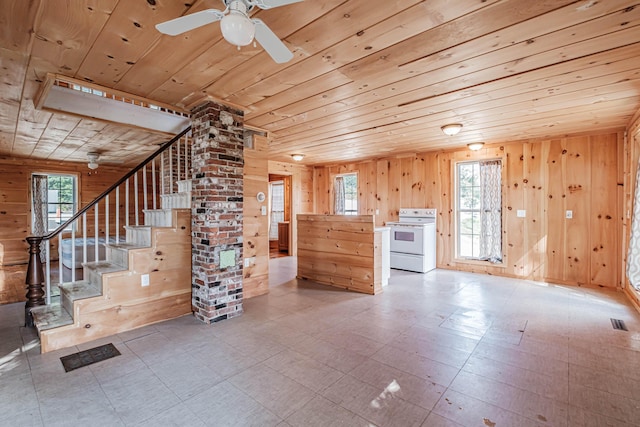 unfurnished living room featuring ceiling fan, wooden ceiling, and wood walls