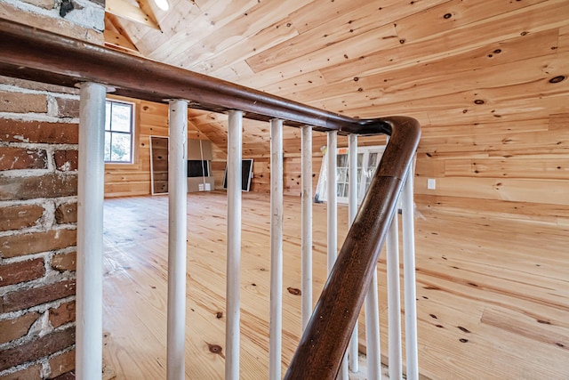 staircase with wood walls, wood ceiling, and vaulted ceiling