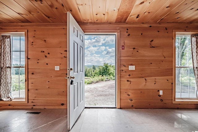 doorway with wood walls, a healthy amount of sunlight, and wooden ceiling