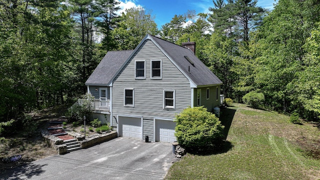 22 Jewett Rd, Raymond, ME 04071 - view of side of home with a chimney, driveway, roof with shingles, a garage, and a lawn