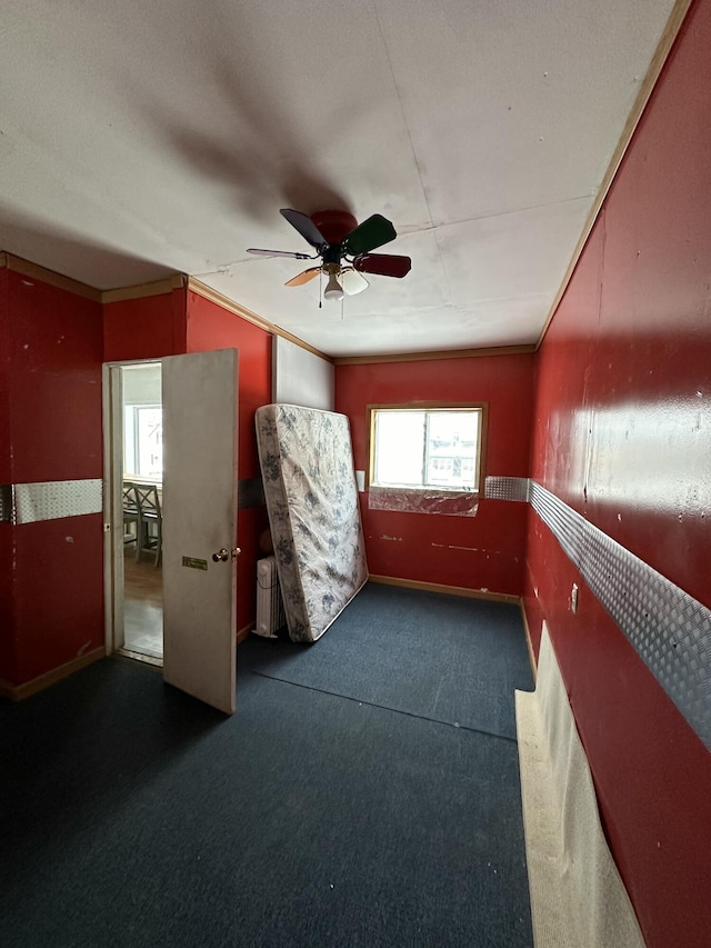 carpeted empty room featuring ceiling fan and ornamental molding