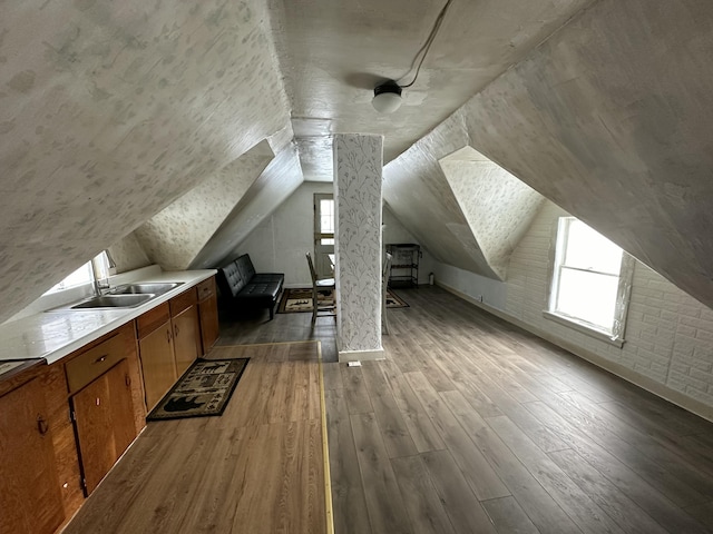 additional living space featuring hardwood / wood-style flooring, vaulted ceiling, and sink