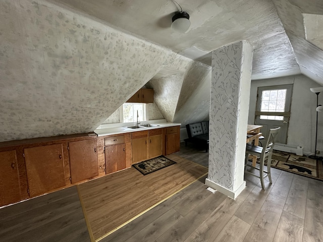 additional living space with lofted ceiling, sink, and light hardwood / wood-style flooring