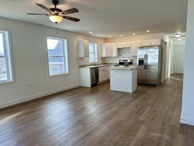 kitchen with white cabinetry, a center island, ceiling fan, stainless steel appliances, and dark hardwood / wood-style floors