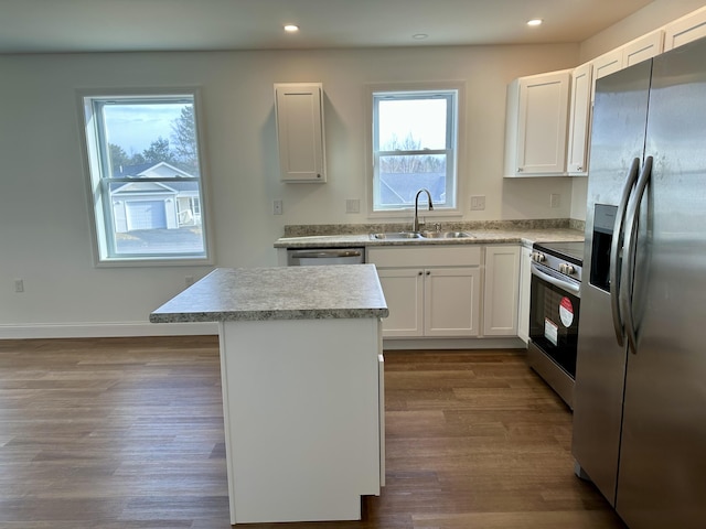 kitchen with stainless steel appliances, dark wood-type flooring, sink, white cabinets, and a kitchen island