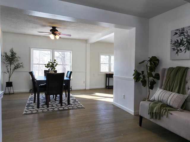 dining area featuring beamed ceiling, ceiling fan, dark hardwood / wood-style floors, and a textured ceiling