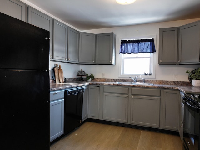 kitchen featuring sink, light hardwood / wood-style flooring, gray cabinetry, and black appliances