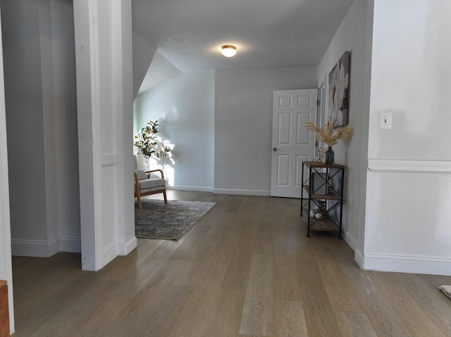 corridor with a textured ceiling and hardwood / wood-style flooring