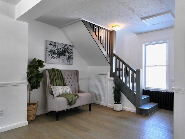 stairway with lofted ceiling, wood-type flooring, and a textured ceiling