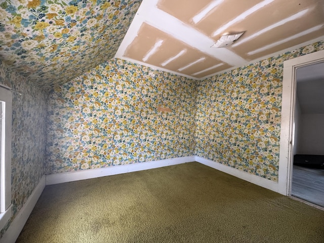 spare room featuring carpet flooring and vaulted ceiling