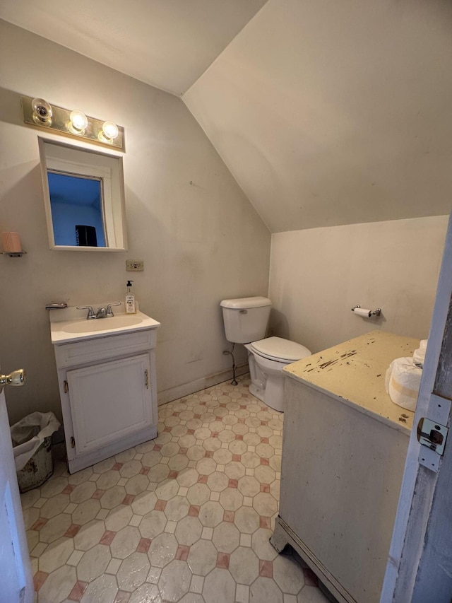 bathroom featuring vanity, toilet, and lofted ceiling