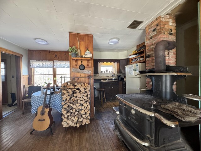 kitchen featuring a wood stove, sink, dark wood-type flooring, and white refrigerator