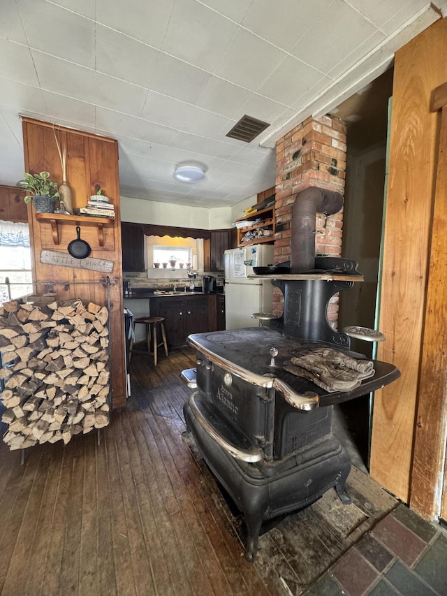 kitchen with a wood stove, white fridge, and dark hardwood / wood-style floors