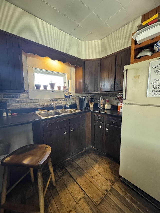 kitchen featuring dark brown cabinetry, sink, white fridge, and dark wood-type flooring