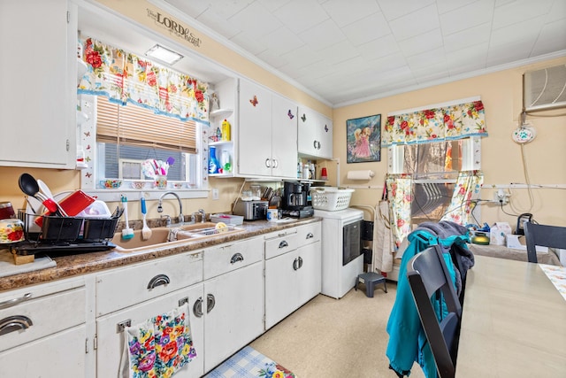 kitchen with white cabinets, washer / dryer, ornamental molding, and sink