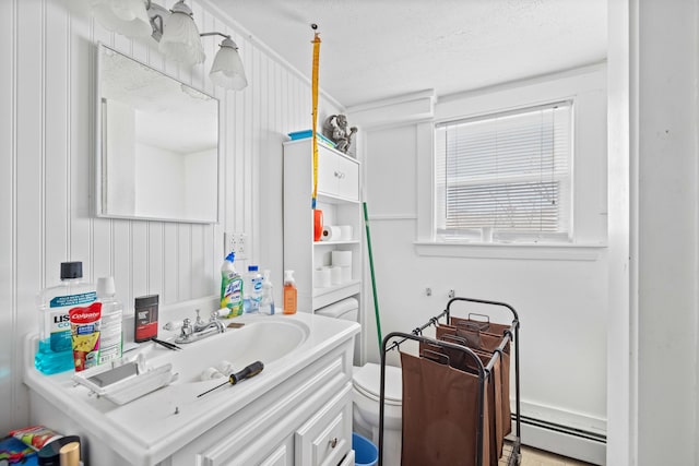 bathroom featuring toilet, vanity, a textured ceiling, and a baseboard heating unit