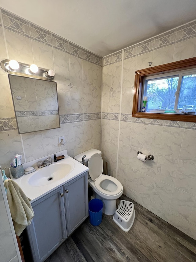 bathroom with hardwood / wood-style flooring, vanity, toilet, and tile walls