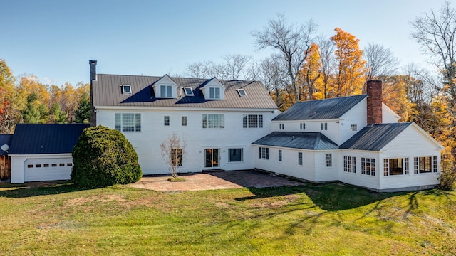 rear view of property featuring a garage, a patio area, and a lawn