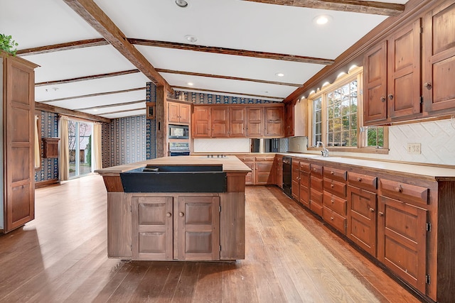 kitchen with black appliances, a center island, beamed ceiling, and light hardwood / wood-style flooring