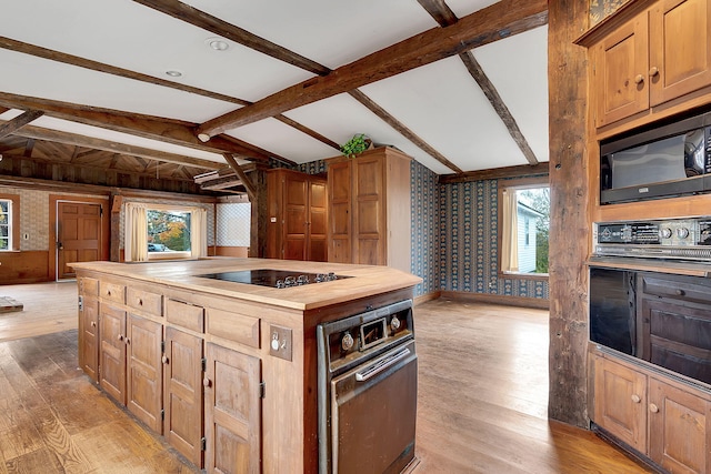 kitchen with black appliances, vaulted ceiling with beams, a kitchen island, butcher block countertops, and light hardwood / wood-style floors