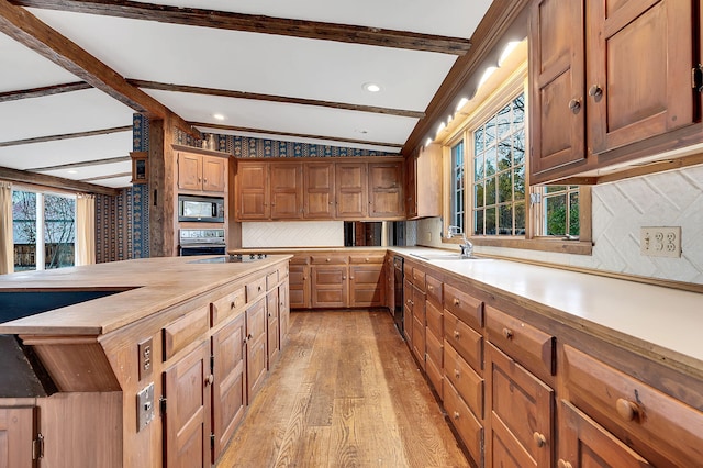 kitchen featuring vaulted ceiling with beams, butcher block countertops, decorative backsplash, black appliances, and light wood-type flooring