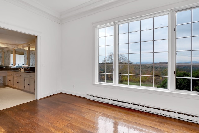 unfurnished room featuring a baseboard radiator, hardwood / wood-style flooring, and crown molding