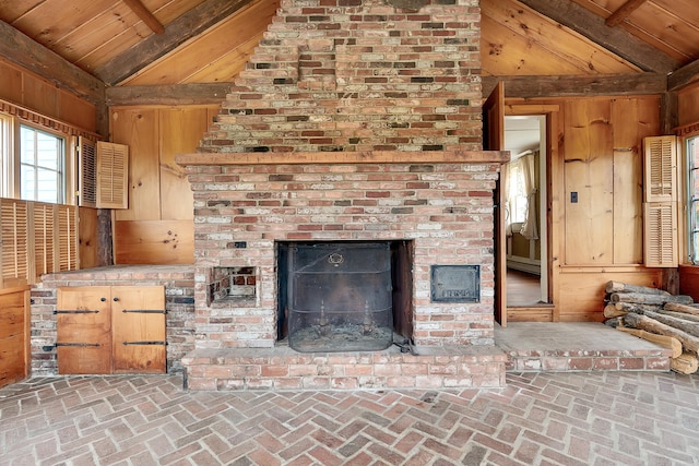 unfurnished living room featuring vaulted ceiling with beams, wood walls, wood ceiling, and a brick fireplace