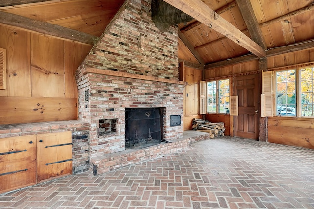 unfurnished living room with beam ceiling, wooden walls, high vaulted ceiling, and wooden ceiling