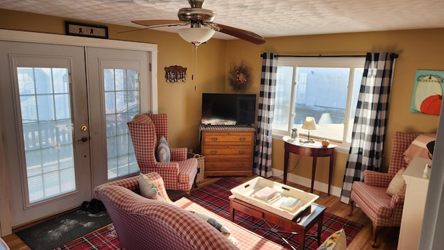 living room featuring french doors, ceiling fan, a textured ceiling, and wood finished floors