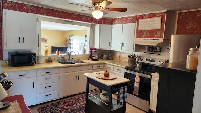 kitchen with black microwave, a sink, white cabinets, light countertops, and stainless steel electric stove