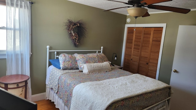 bedroom with baseboards, a ceiling fan, a closet, and wood finished floors